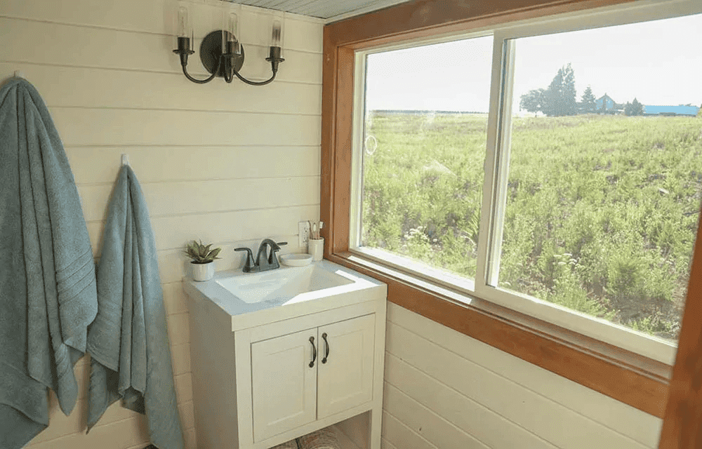 La salle de bain comme le reste de la mini maison est baigné de lumière grâce à une grande fenêtre offrant une vue sur la nature